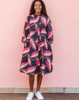 The model is wearing navy blue dress with black, pink and baby pink chrysalis