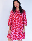 Model wearing red dress with pink flower print.
