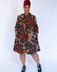 Model wearing orange, brown and green dress.