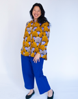 Model wearing long sleeved orange and purple geometric print shirt.