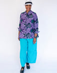 Model wearing long sleeved shirt with purple and green fish print.