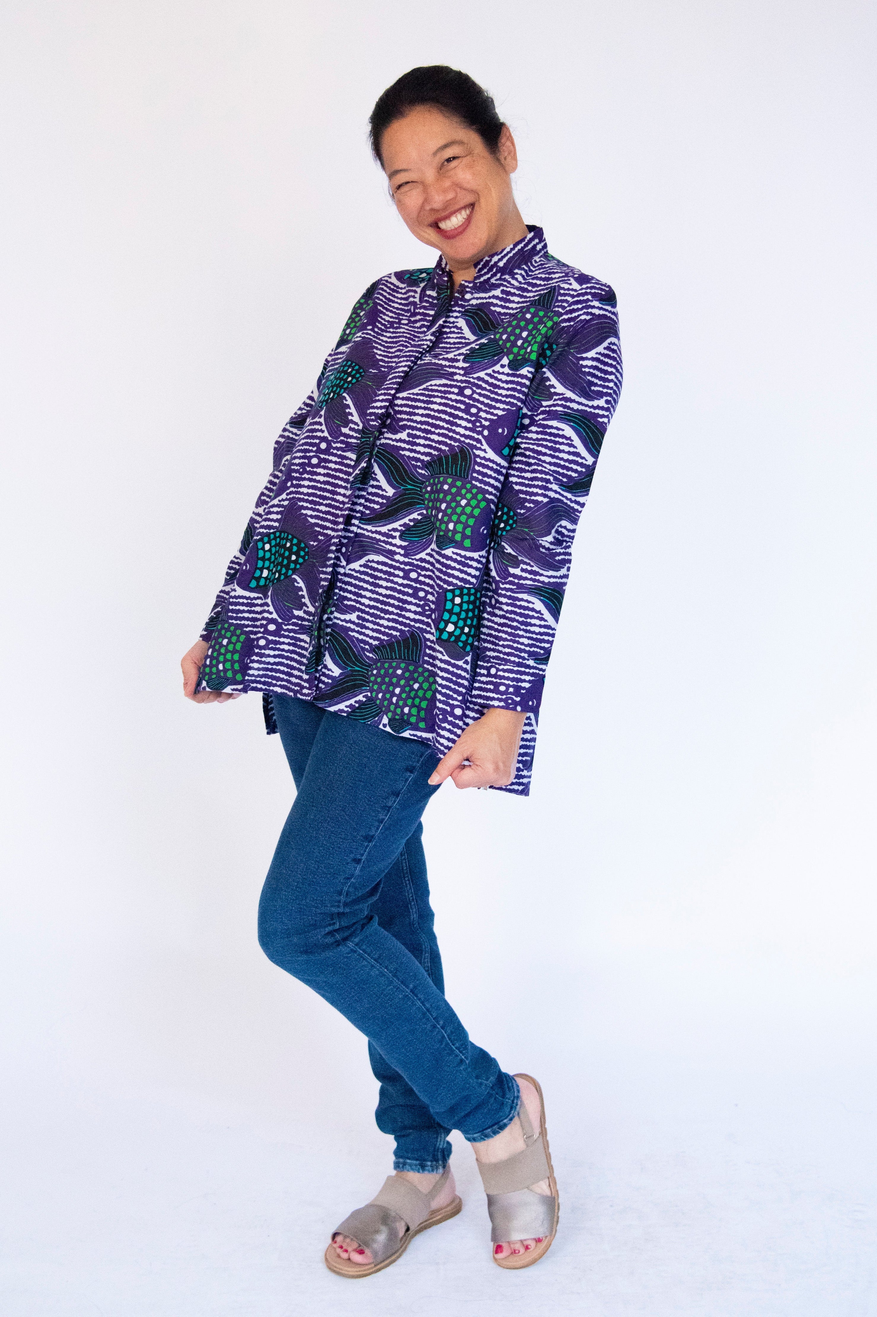 Model wearing long sleeved shirt with purple and green fish print.
