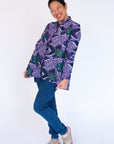 Model wearing long sleeved shirt with purple and green fish print.