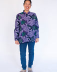 Model wearing long sleeved shirt with purple and green fish print.