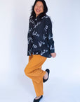 Model wearing black long sleeved shirt with white music print design.