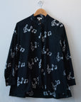 Display of black long sleeved shirt with white music print design.