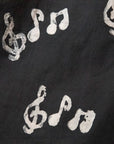 Close up display of black long sleeved shirt with white music print design, fabric.