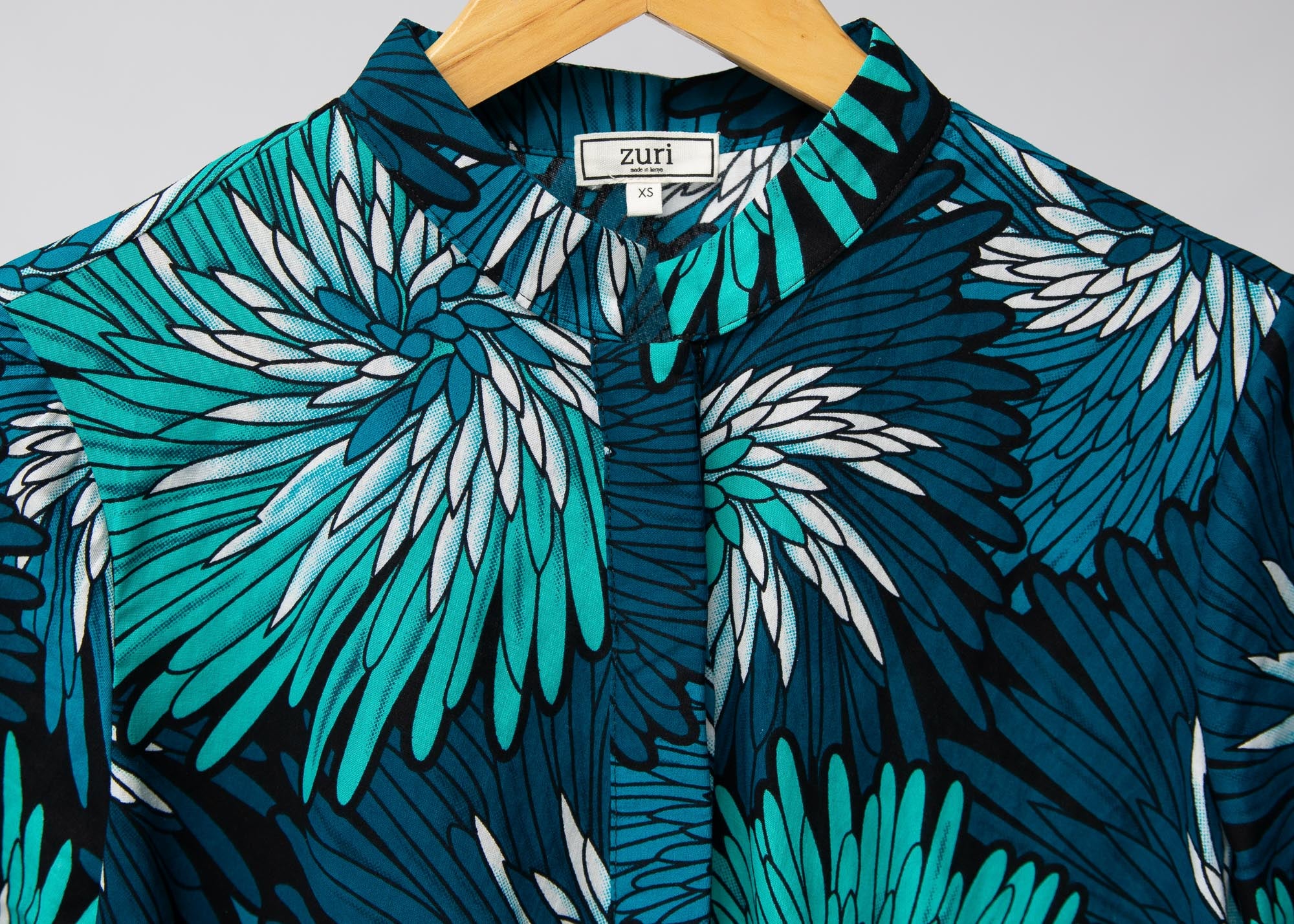 Display of turquoise, black, pacific blue, slate and white feathered spiral print dress