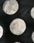 Close up display of black sleeveless shirt with white circles print, fabric.