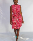 Model wearing red sleeveless dress with white dots.