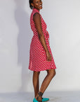 Model wearing red sleeveless dress with white dots.