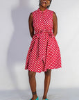 Model wearing red sleeveless dress with white dots.