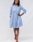 Model wearing blue dress with white polka dots.