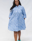 Model wearing blue dress with white polka dots.