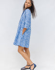 Model wearing blue dress with white polka dots.