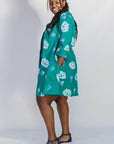 Model wearing teal dress with white cat print.