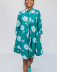 Model wearing teal dress with white cat print.