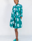 Model wearing teal dress with white cat print.