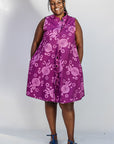 Model wearing purple dress with pink beet print.