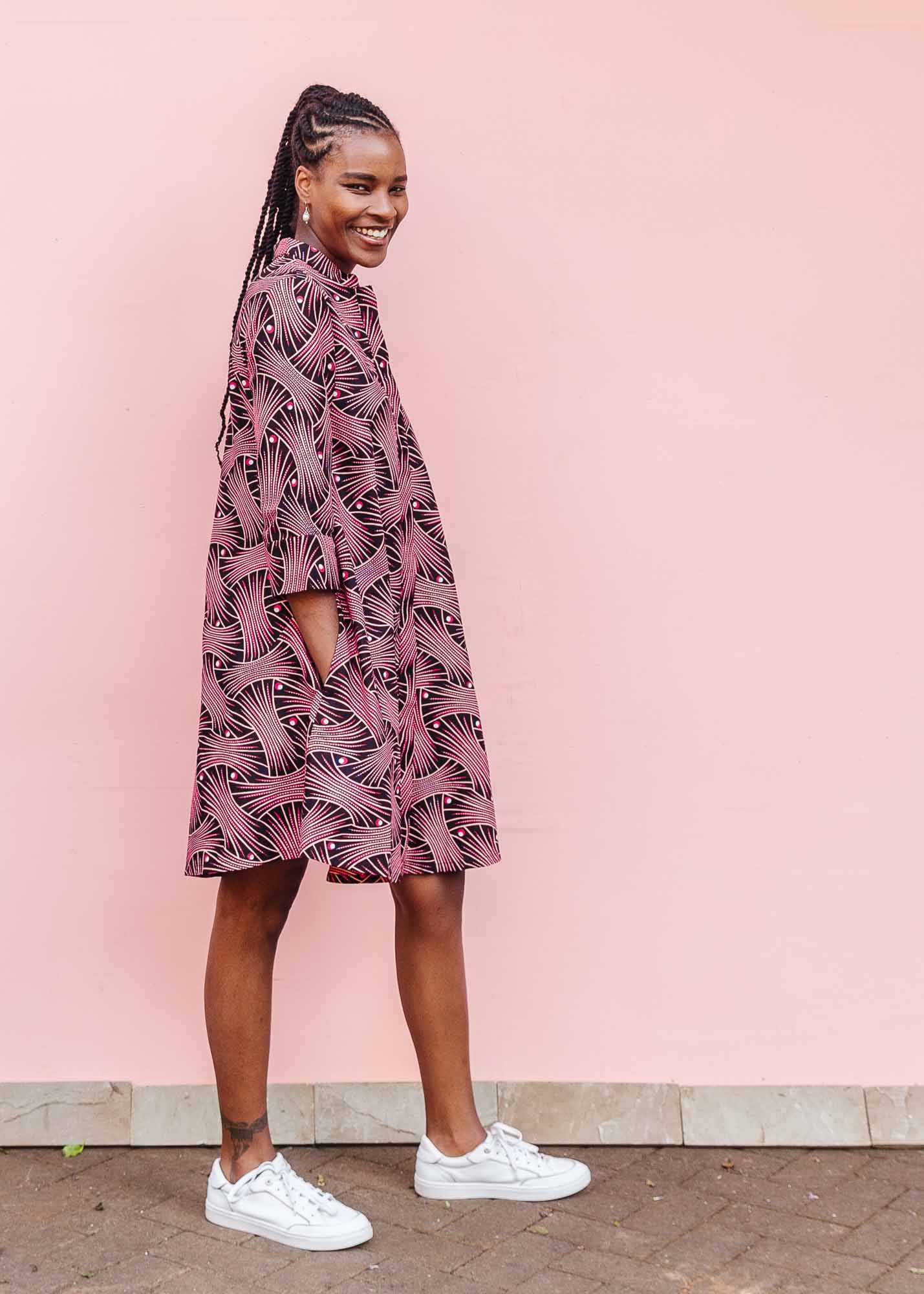 The model is wearing coral, pink, white and navy blue colored dress