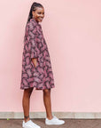The model is wearing coral, pink, white and navy blue colored dress