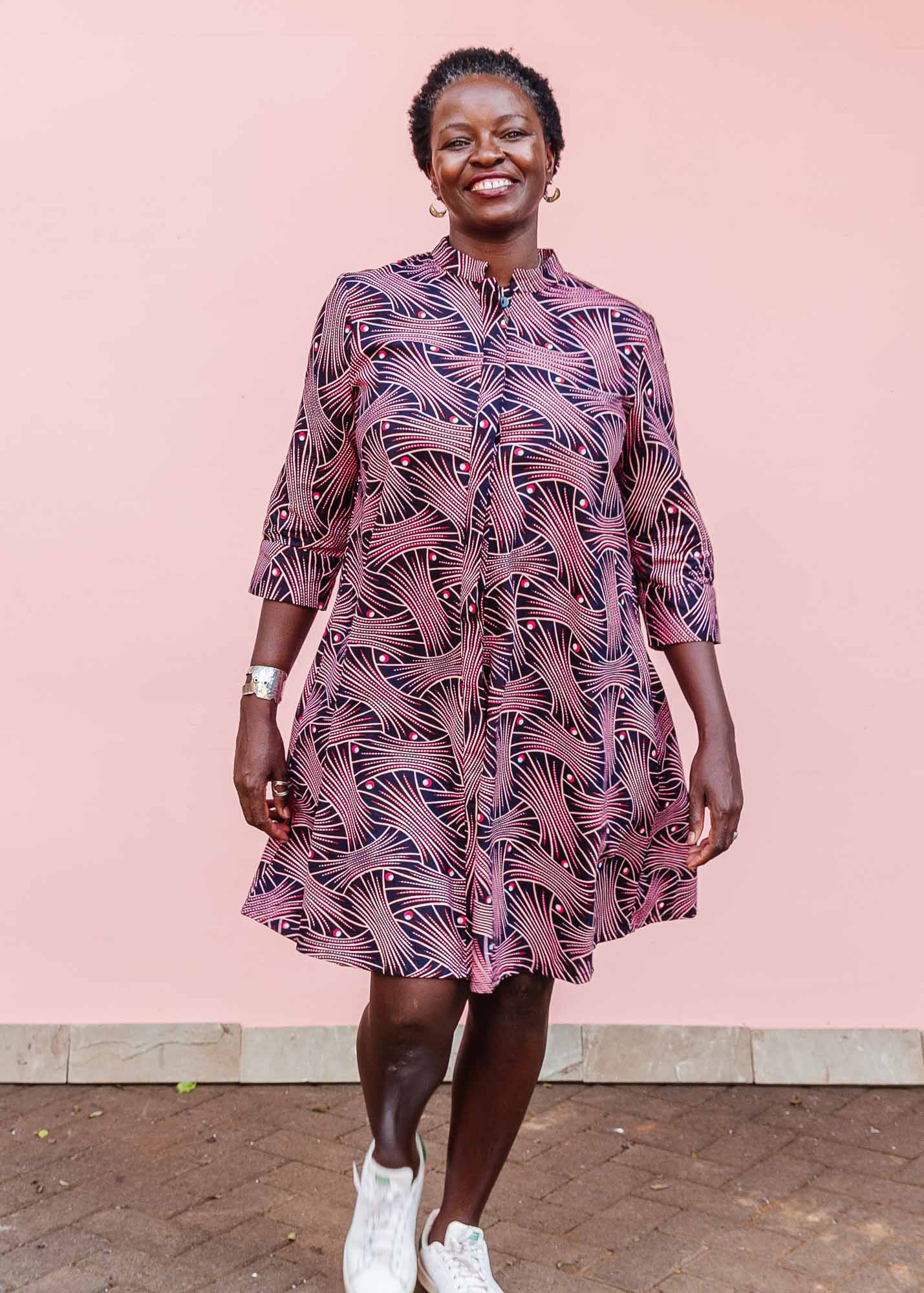 The model is wearing coral, pink, white and navy blue colored dress