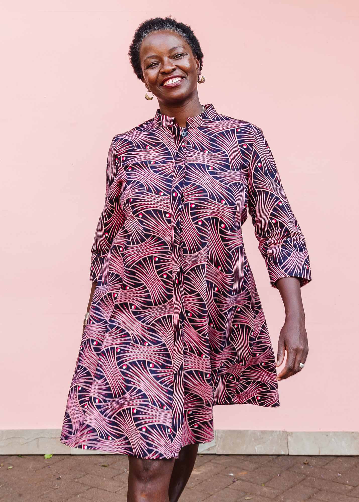 The model is wearing coral, pink, white and navy blue colored dress