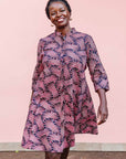 The model is wearing coral, pink, white and navy blue colored dress