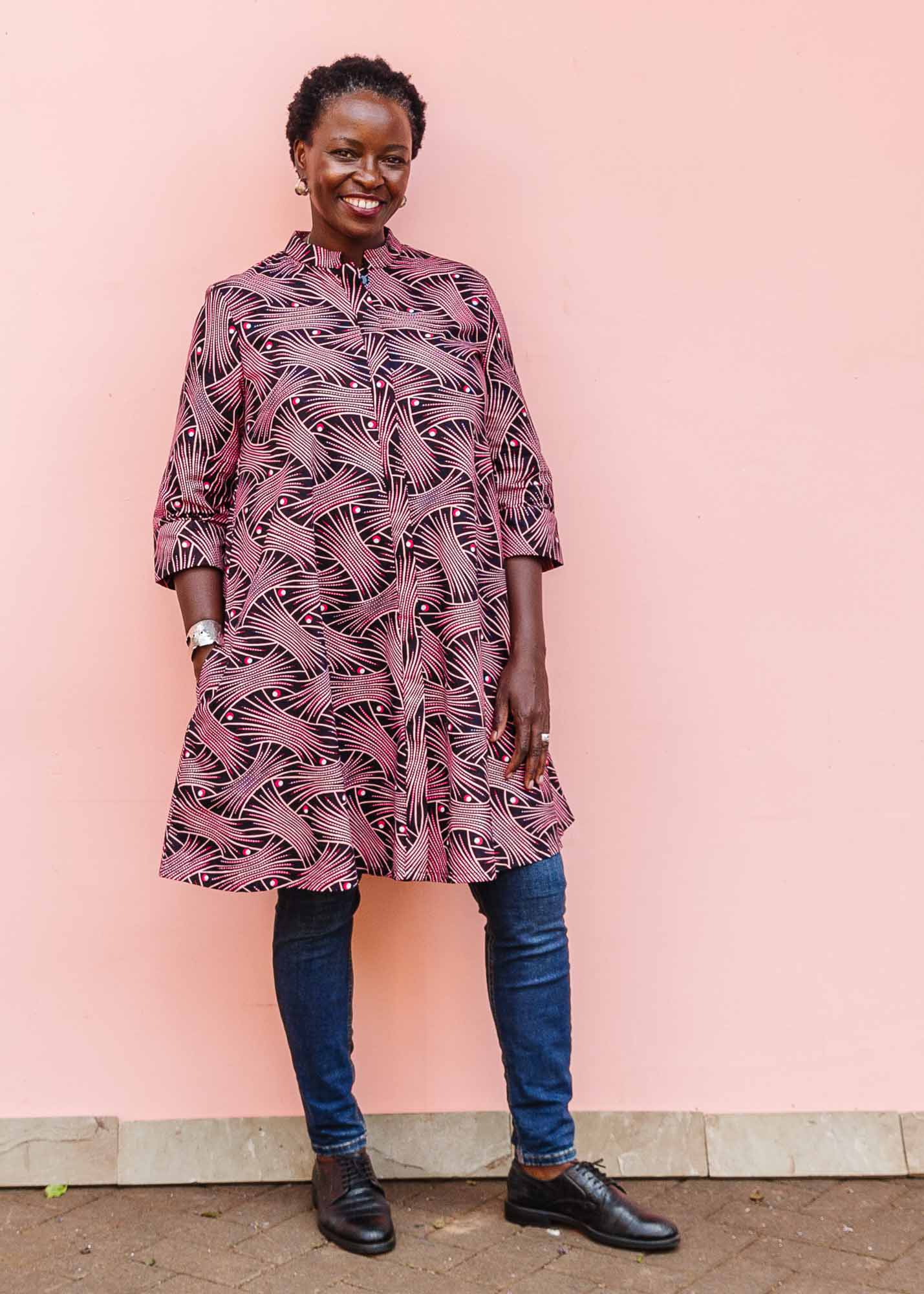 The model is wearing coral, pink, white and navy blue colored dress