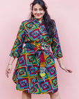The model is wearing geometric print with rainbow colored dress  paired with patchwork belt