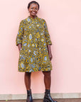 The model is wearing black dress with white and yellow botanical print