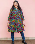 The model is wearing geometric print with rainbow colored dress 