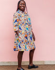 The model is wearing multi-colored paisley print dress