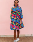 The model is wearing colorful mandala print dress