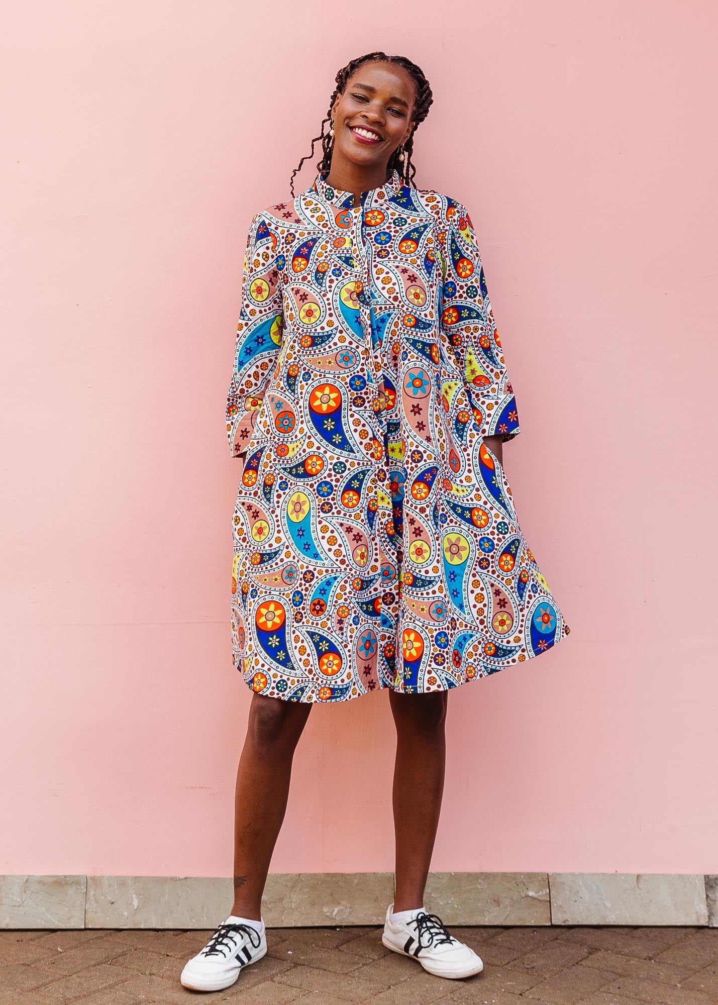 The model is wearing multi-colored paisley print dress