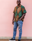 The model is wearing brown, camel, green and black diamond shaped geometric print shirt