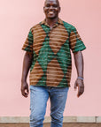 The model is wearing brown, camel, green and black diamond shaped geometric print shirt