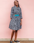 The model is wearing black dress with white rectangles