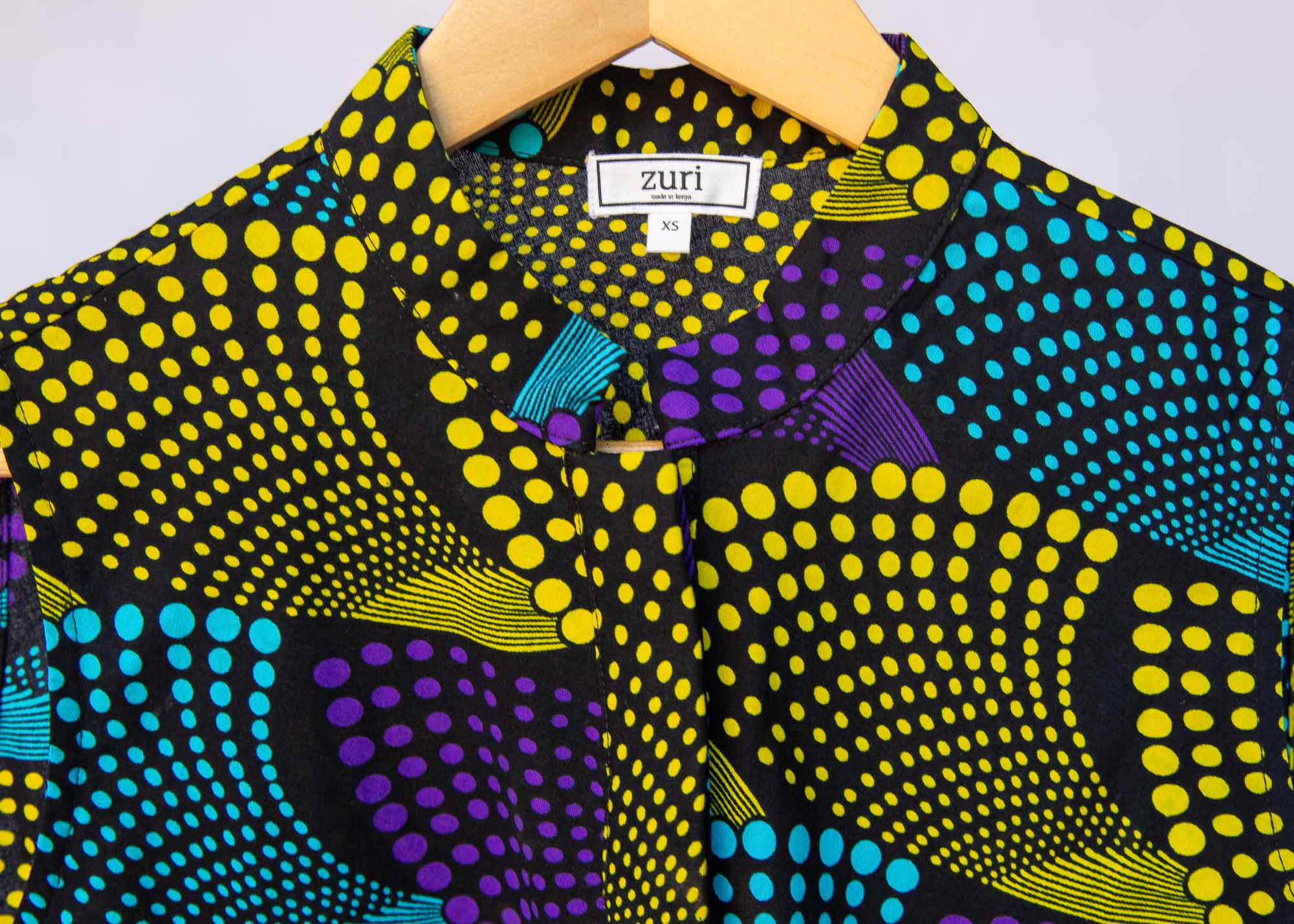 Display of black dress with purple , yellow and turquoise dotted fans
