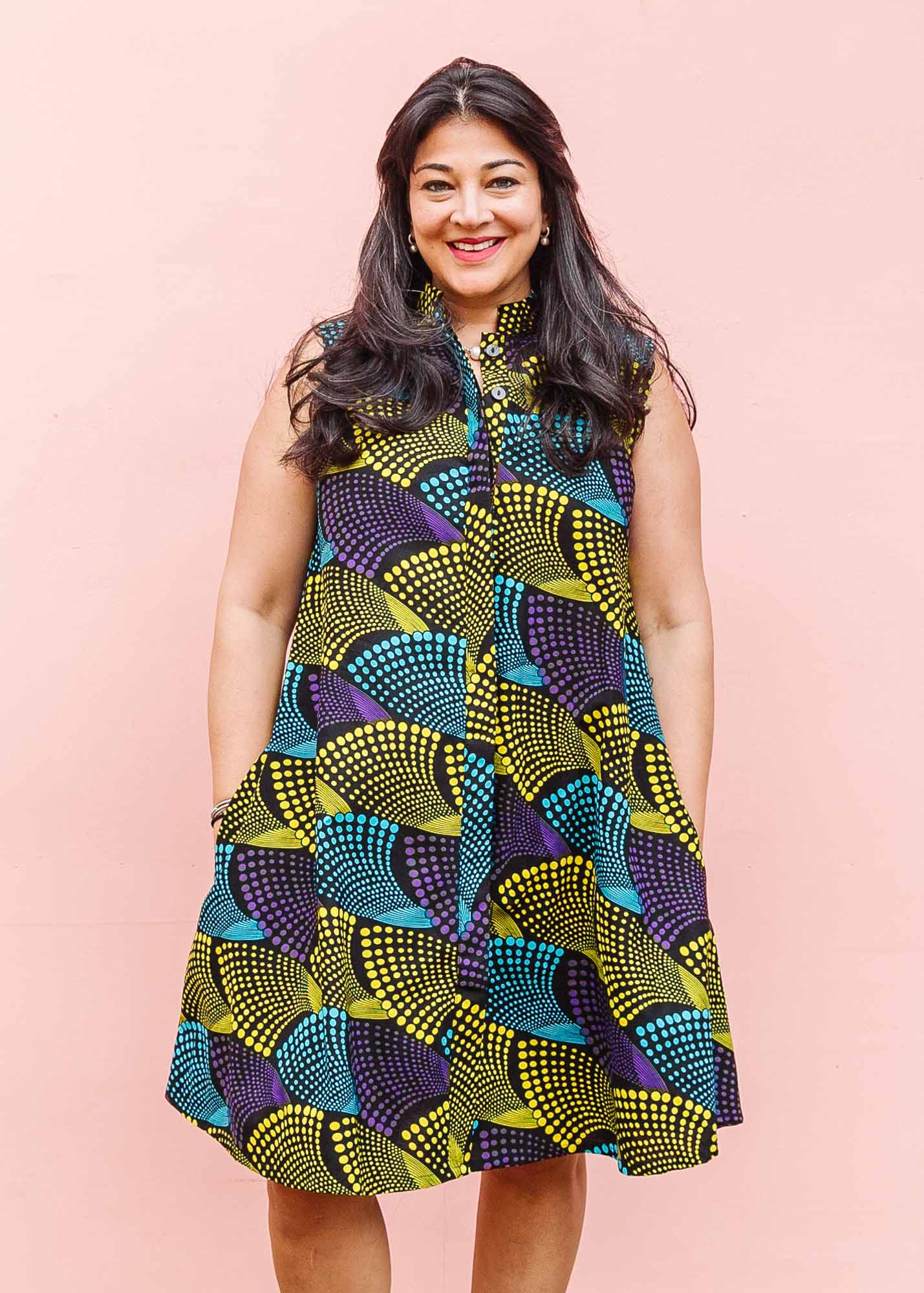 The model is wearing black dress with purple , yellow and turquoise dotted fans