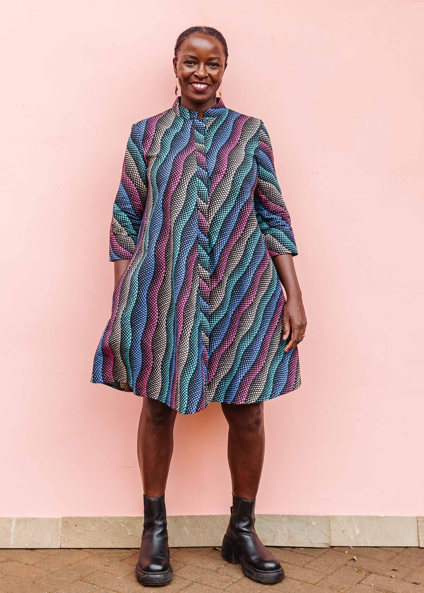The model is wearing pink, blue, turquoise and beige abstract line dress.