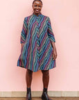 The model is wearing pink, blue, turquoise and beige abstract line dress.