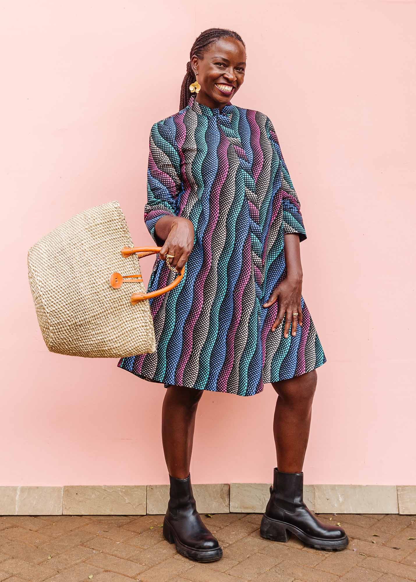 The model is wearing pink, blue, turquoise and beige abstract line dress.