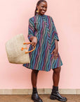 The model is wearing pink, blue, turquoise and beige abstract line dress.