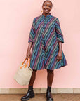 The model is wearing pink, blue, turquoise and beige abstract line dress.