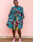 The model is wearing turquoise, black, slate, white and red abstract print dress