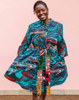 The model is wearing turquoise, black, slate, white and red abstract print dress