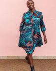 The model is wearing turquoise, black, slate, white and red abstract print dress