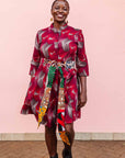The model is wearing merlot red, brown, red , coral and white abstract line print dress