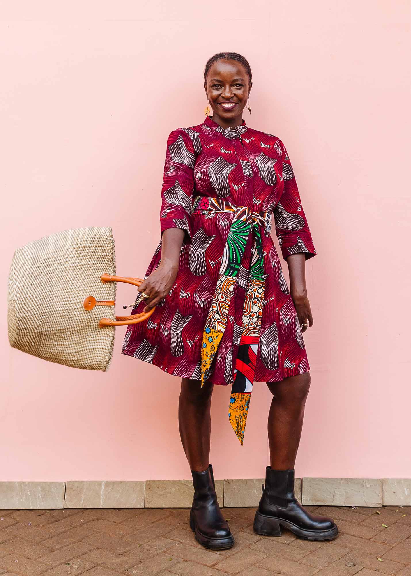 The model is wearing  merlot red, brown, red , coral and white abstract line print dress